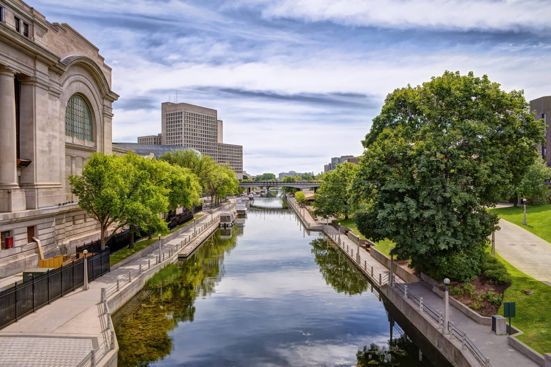 Urban scene of buildings and Rideau canal, cloudy sky in background.