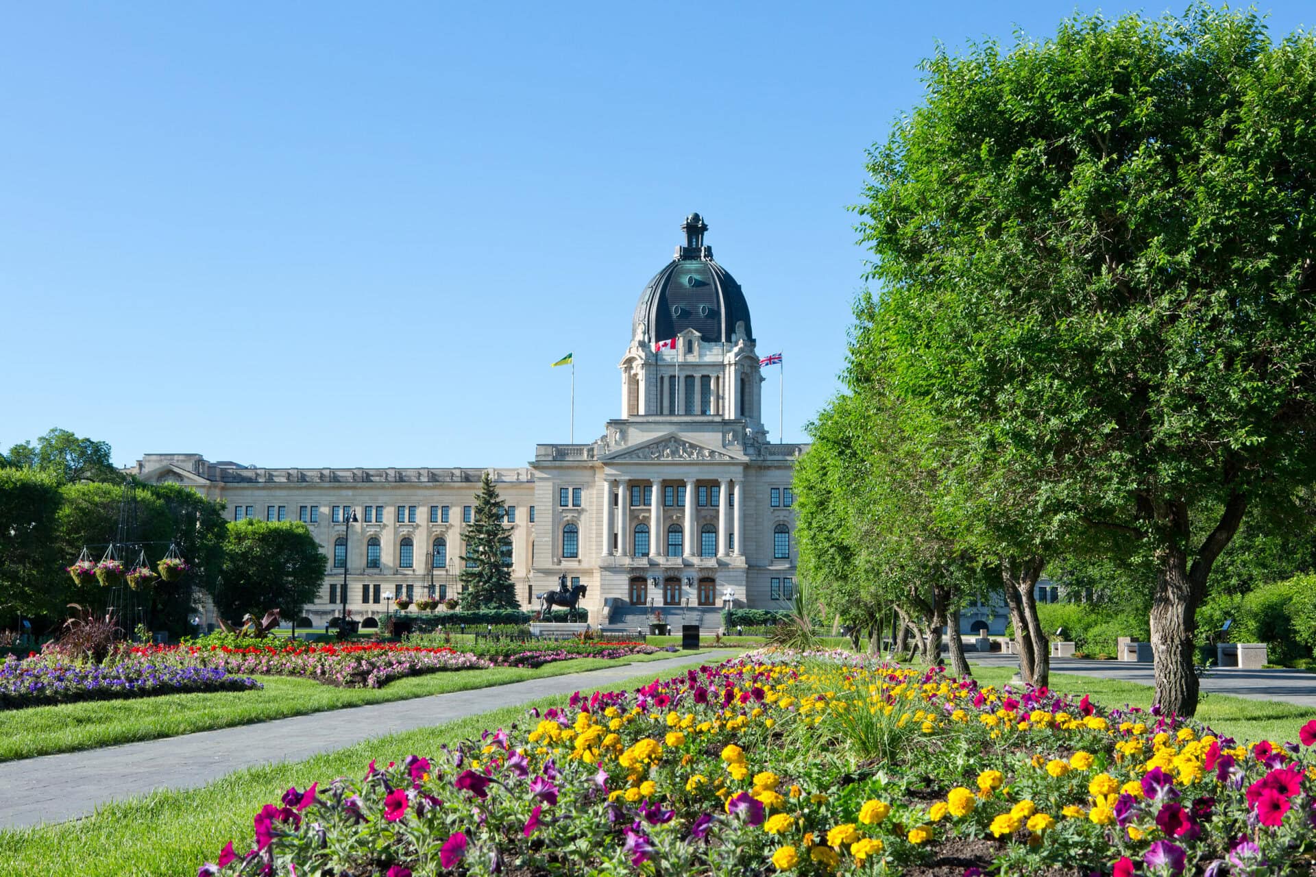Exterior view of Saskatchewan's legislative building, with flowers in bloom on the lawn gardens