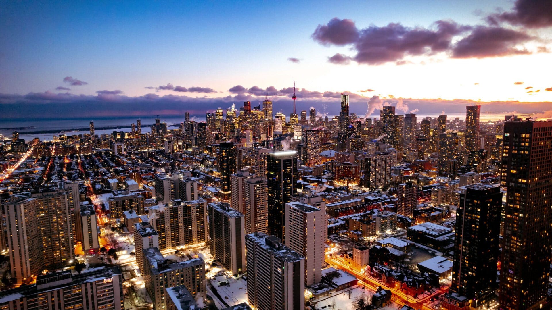 Aerial view of a vibrant cityscape of Toronto including CN Tower, with tall buildings and lights