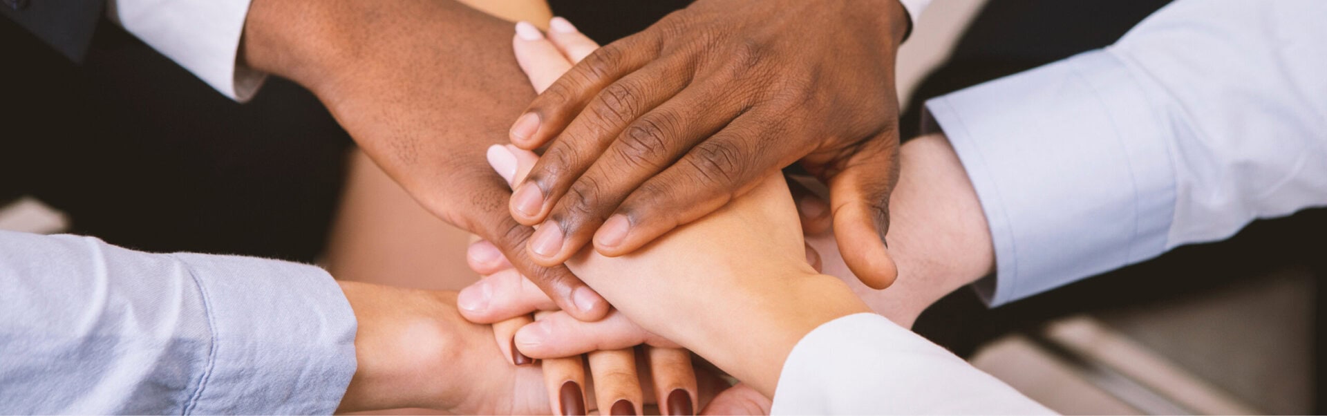 A diversity of employees put their hands together
