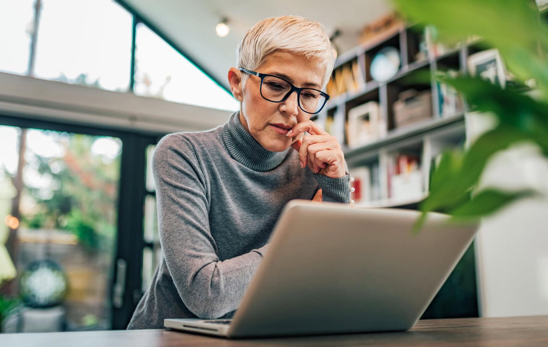 A workplace leader thinks as she looks at her laptop from her home office.