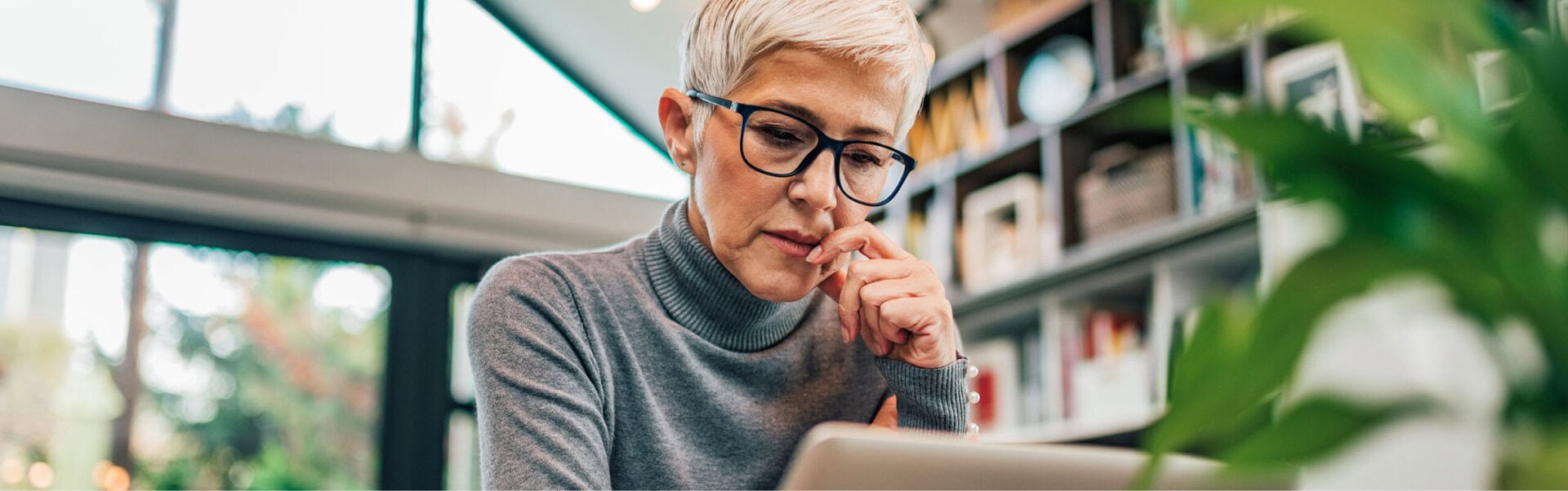 A workplace leader thinks as she looks at her laptop from her home office.