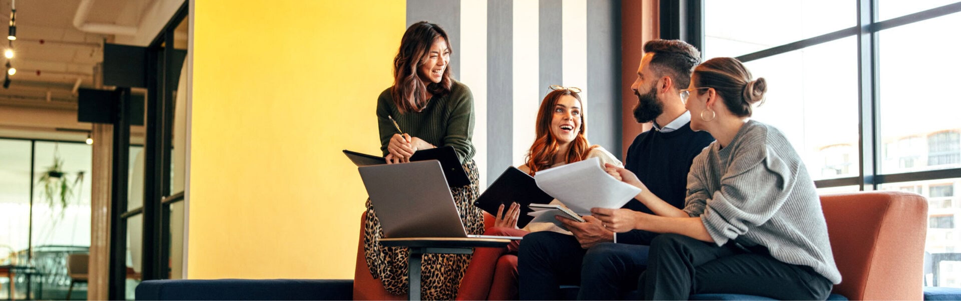 Four employees smile while collaborating in a Canadian office
