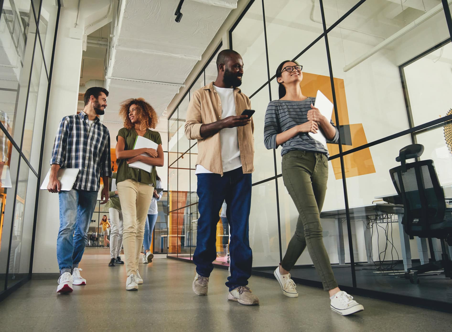 A group of professionals walking down a hallway, engaged in conversation, highlighting teamwork and collaboration from a leadership workshop.