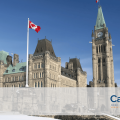 Side view of Canadian parliament buildings with a Canadian flag in the forefront